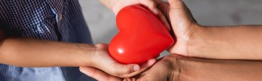 Afro-Amerikan anne ve kızının ellerinde Red Heart modelinin web sitesi başlığı