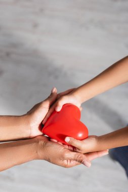 Afrikalı Amerikalı anne ve çocuğun ellerinde kırmızı kalp modelinin yüksek açılı görüntüsü