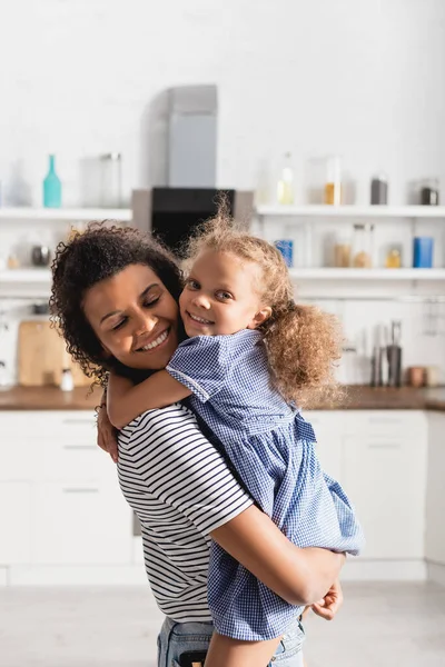 Afro Amerikalı Kız Kameraya Bakıyor Annesini Kucaklıyor Mutfakta Onu Tutuyor — Stok fotoğraf
