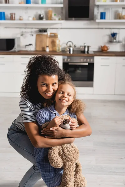 Jovem Afro Americana Abraçando Filha Excitada Com Ursinho Pelúcia Enquanto — Fotografia de Stock