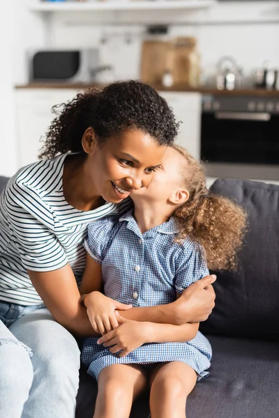 African American Girl Whispering Ear Mother While Sitting Sofa Home — Stock Photo, Image