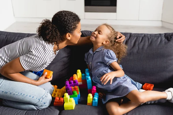 African American Nanny Touching Hair Girl While Sitting Sofa Multicolored — Stock Photo, Image