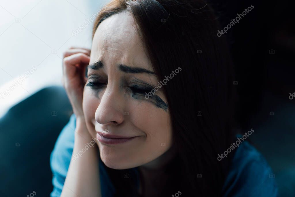 depressed woman with flowed mascara crying at home 