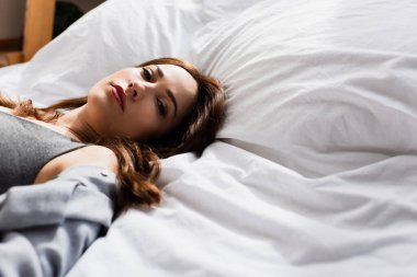 Yatakta uzanmış kameraya bakan depresif bir kadının seçici odağı.