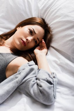 Üzgün bir kadının yüksek açılı görüntüsü Yatakta yatıp başka tarafa bakıyor