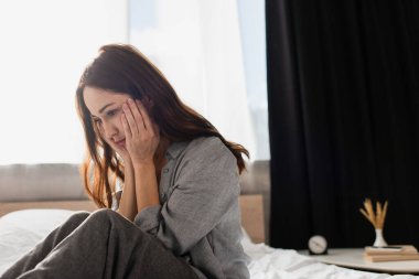 depresif esmer kadın evde yüzüne dokunuyor.