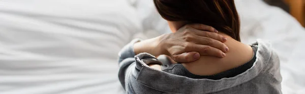 寝室で首の痛みに苦しむブルネットの女性のウェブサイトのヘッダー — ストック写真