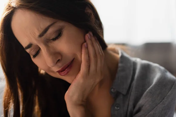 Mulher Morena Triste Com Olhos Fechados Tocando Rosto Enquanto Sofre — Fotografia de Stock