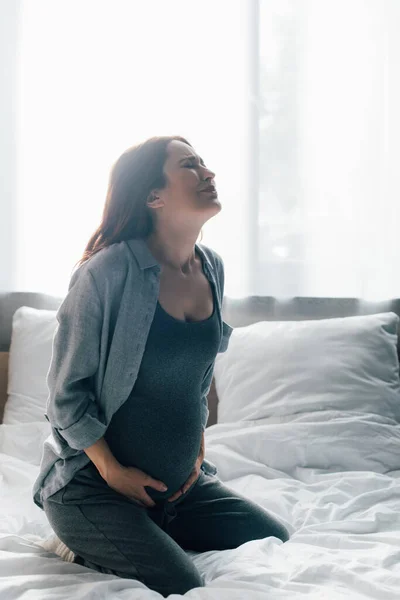 Hamile Kadın Yatakta Otururken Acıdan Kıvranıyor — Stok fotoğraf