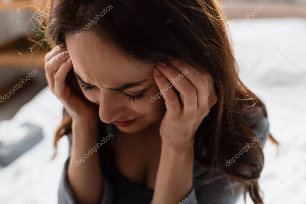 woman suffering from pain and touching head at home