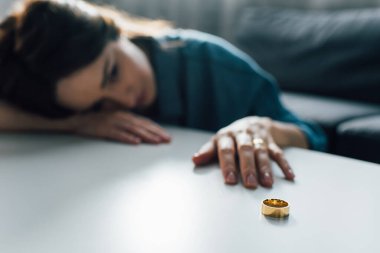 Sehpadaki altın yüzüğe ulaşan üzgün kadının seçici odağı, boşanma konsepti. 