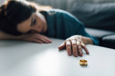 selective focus of upset woman reaching golden ring on coffee table, divorce concept  clipart