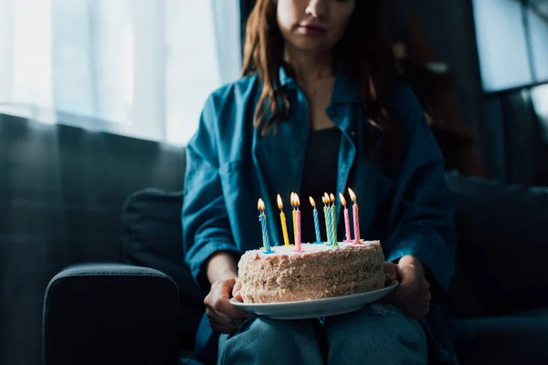 ろうそくのあるお誕生日ケーキを持つ悲しい女性のクロップドビュー — ストック写真