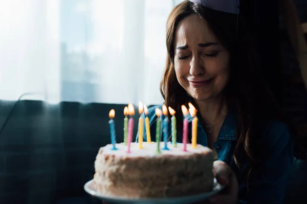 キャンドルでお誕生日ケーキを持ちながら泣く悲しい女性の選択的焦点 — ストック写真