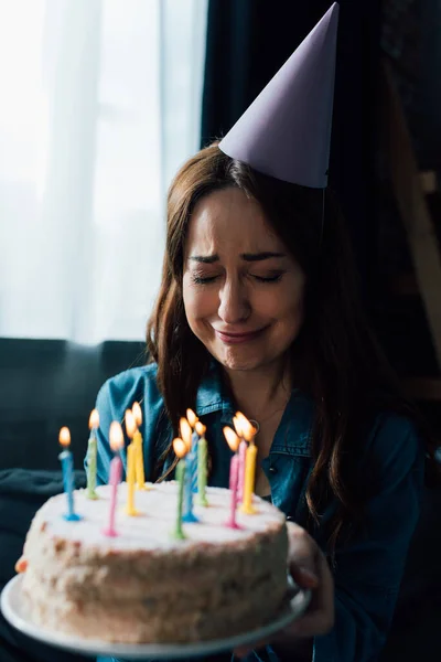 キャンドルでお誕生日ケーキを持ちながら泣く動揺女性の選択的焦点 — ストック写真