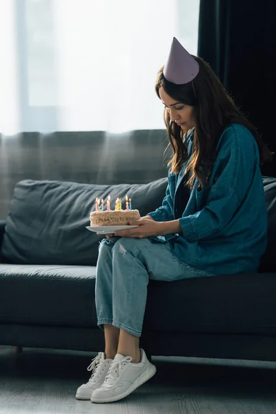 Sad Woman Party Cap Sitting Sofa Holding Birthday Cake Candles — Stock Photo, Image