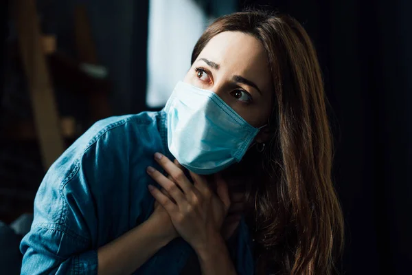 Φοβισμένη Μελαχρινή Γυναίκα Μπλε Ιατρική Μάσκα Αγγίζοντας Λαιμό Στο Σπίτι — Φωτογραφία Αρχείου