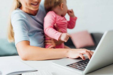 Kızı evde tutarken dizüstü bilgisayar kullanan serbest çalışanların seçici odağı 