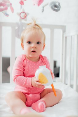 Bebek monitörünü tutan ve beşikteki kameraya bakan kızın seçici odak noktası 