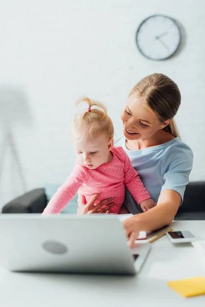 Selective Focus Mother Holding Baby Girl Gadgets Table — Stock Photo, Image