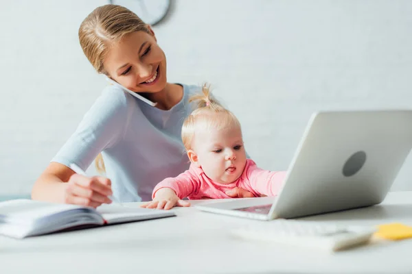 Selective Focus Infant Sitting Mother Talking Smartphone Working Home — Stock Photo, Image