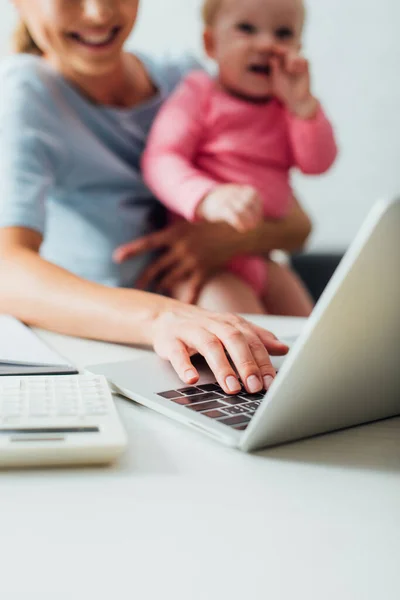 Selective Focus Mother Holding Infant Daughter Using Laptop Calculator Table — Stock Photo, Image