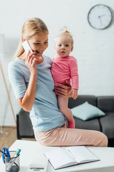 Selective Focus Woman Talking Smartphone Holding Baby Girl Stationery Table — Stock Photo, Image