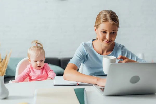 Enfoque Selectivo Mujer Con Taza Trabajo Ordenador Portátil Cerca Niña — Foto de Stock