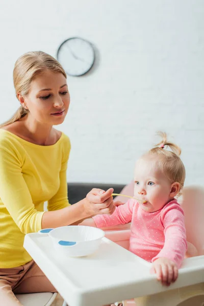 Selective Focus Mother Spoon Feeding Infant Daughter Highchair — Stock Photo, Image