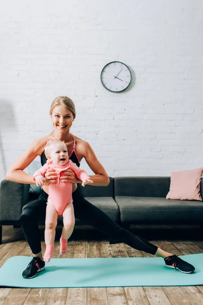 Desportista Fazendo Lunges Enquanto Segurando Bebê Menina Tapete Fitness Casa — Fotografia de Stock