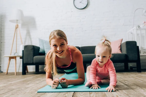 Sportlerin Beim Planken Neben Kind Auf Fitnessmatte — Stockfoto