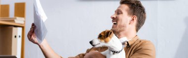 Jack Russell Terrier ile çalışırken belgelere bakan genç işadamının yatay görüntüsü  