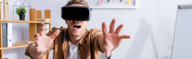 Ofiste VR kulaklığı kullanırken heyecanlanan iş adamının yatay görüntüsü