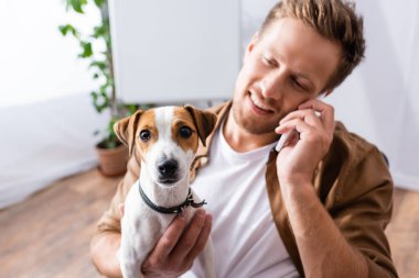 Jack Russell terrier köpeğini tutarken cep telefonuyla konuşan işadamlarının seçici odak noktası