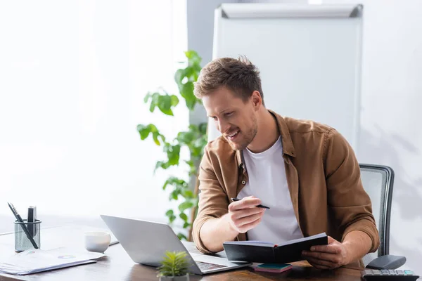 Young Businessman Holding Notebook Pen While Looking Laptop Office — Stock Photo, Image