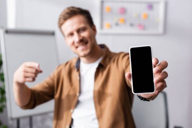 İşadamlarının seçici odağı ofiste boş ekranlı akıllı telefonu işaret ediyor. 