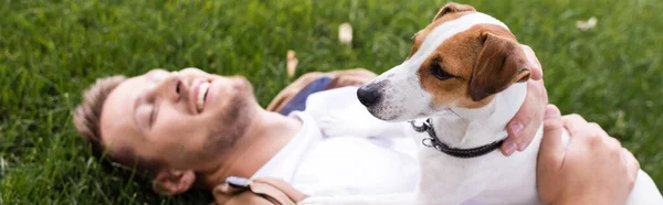 Pozioma Koncepcja Człowieka Leżącego Trawniku Zamkniętymi Oczami Przytulającego Psa Terrier — Zdjęcie stockowe