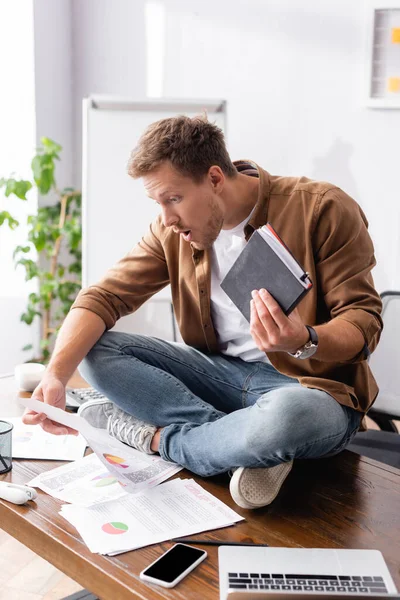 Selective Focus Shocked Businessman Holding Notebook Papers Digital Devices Office — Stock Photo, Image