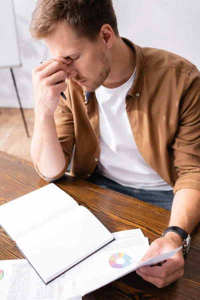 Selective Focus Tired Businessman Holding Papers Notebook Table Office — Stock Photo, Image