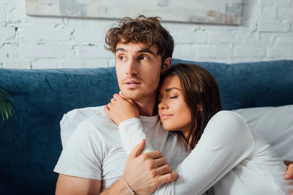 Young Man Sitting Bed Embracing Girlfriend Looking Away — Stock Photo, Image