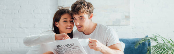 Панорамный снимок женщины, смотрящей на газету рядом с парнем с чашкой кофе дома