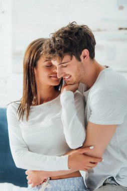 Genç bir kadın yatak odasında pijamalı sevgilisine dokunuyor. 