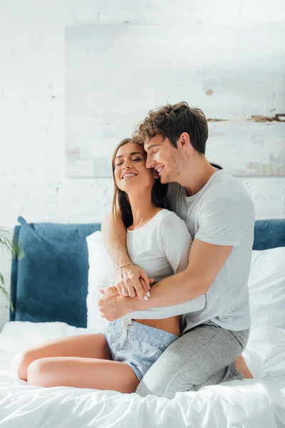 Jeune Homme Étreignant Petite Amie Souriante Pyjama Sur Lit Maison — Photo