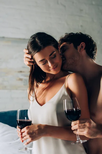 赤身裸体男人在卧室用酒杯亲吻迷人女人的选择性焦点 — 图库照片