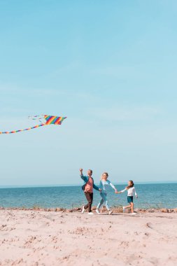 Ailenin seçici odak noktası deniz kenarında uçurtmayla koşmak 