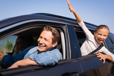 Selective focus of man driving car near daughter and wife during vacation  clipart