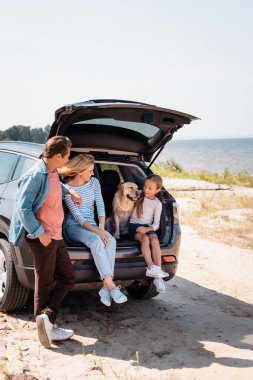 Golden Retriever 'lı kızı plajdaki araba bagajında görmek isteyen seçici ebeveynler. 