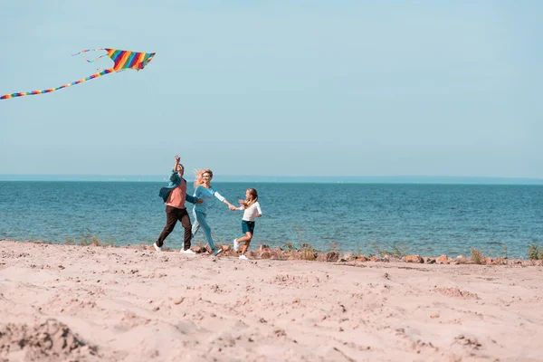 海の近くのビーチの砂の上を走るカイトと家族の選択的な焦点 — ストック写真