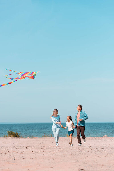 Selective focus of family running with kite on beach during weekend 