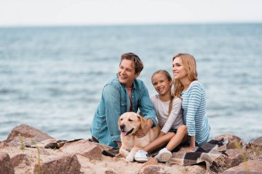 Golden Retriever 'ın sahilde battaniyede oturduğu ailenin seçici odağı. 